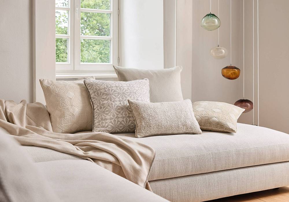 Helles Sofa mit dekorativen Kissen aus strukturierten Möbelstoffen in modernem Wohnraum.